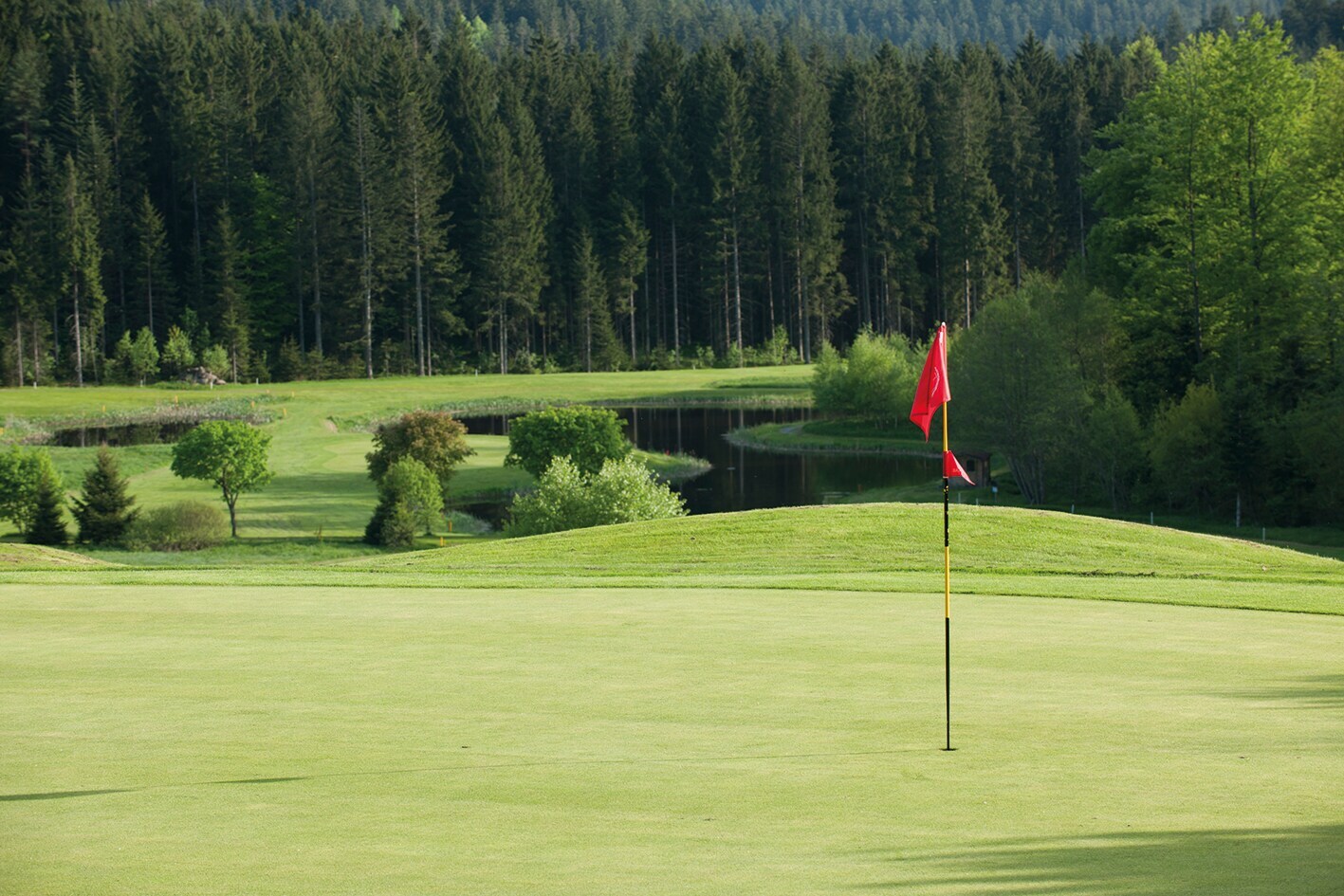 Eine rote Fahne auf dem hügeligen Golfplatz