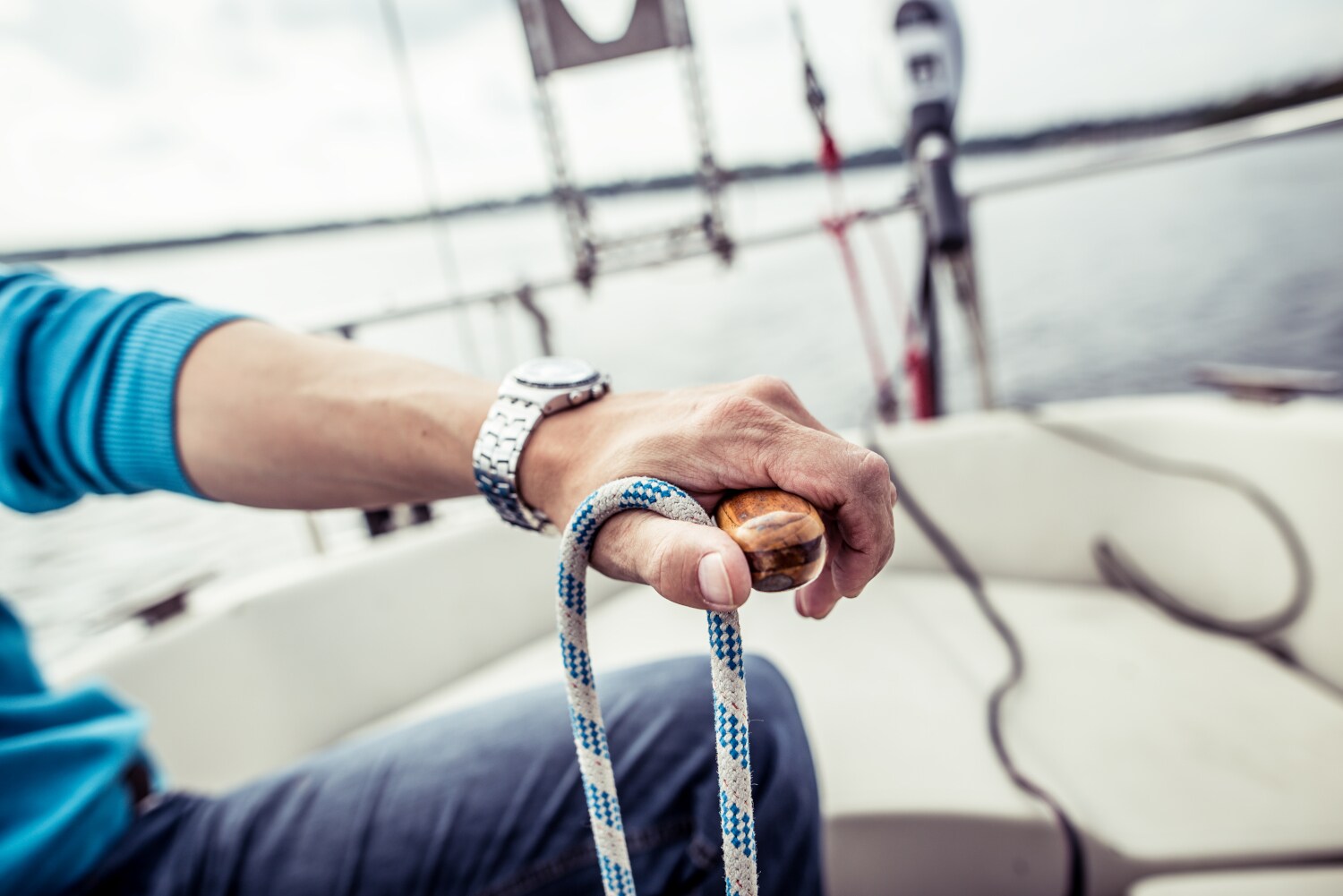 Die linke Hand eines Mannes hält das Steuer eines Segelboots Die linke Hand eines Mannes hält das Steuer eines Segelboots