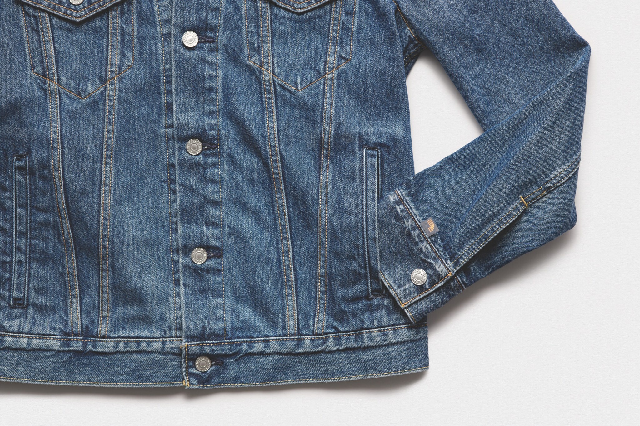 Eine Jeansjacke die auf einer weißen glatten Oberfläche liegt mit einem Mikrochip, der aus dem Ärmel heraussteht Eine Jeansjacke die auf einer weißen glatten Oberfläche liegt mit einem Mikrochip, der aus dem Ärmel heraussteht