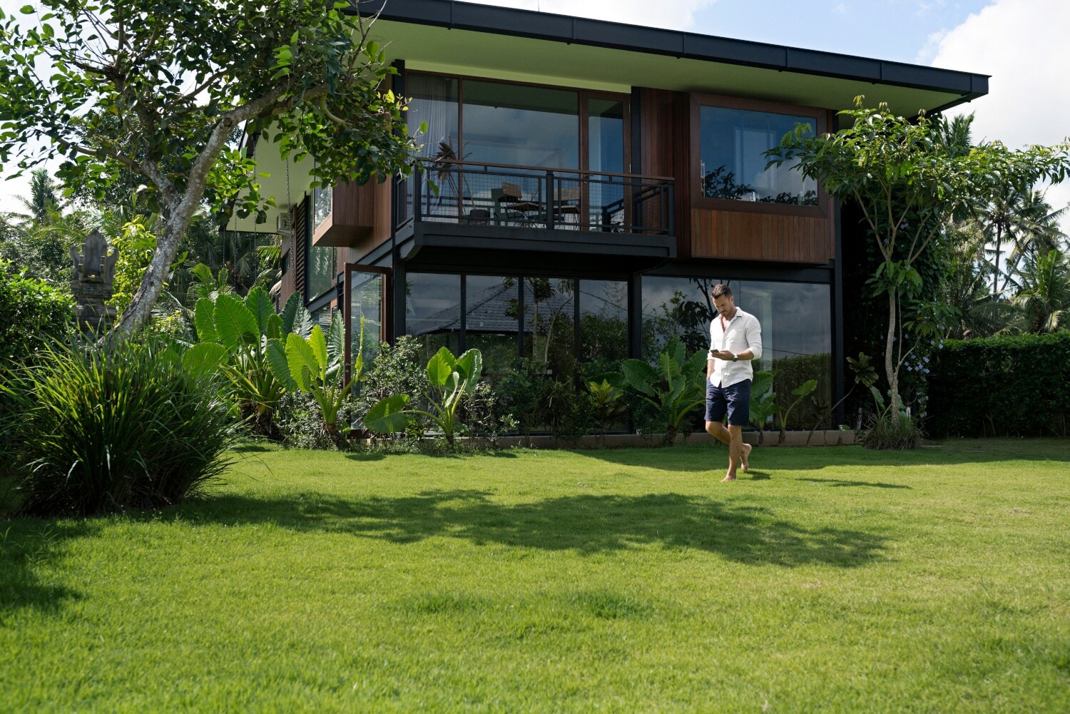 Ein Mann läuft mit Handy in der Hand über den Rasen hinter einem Haus Ein Mann läuft mit Handy in der Hand über den Rasen hinter einem Haus