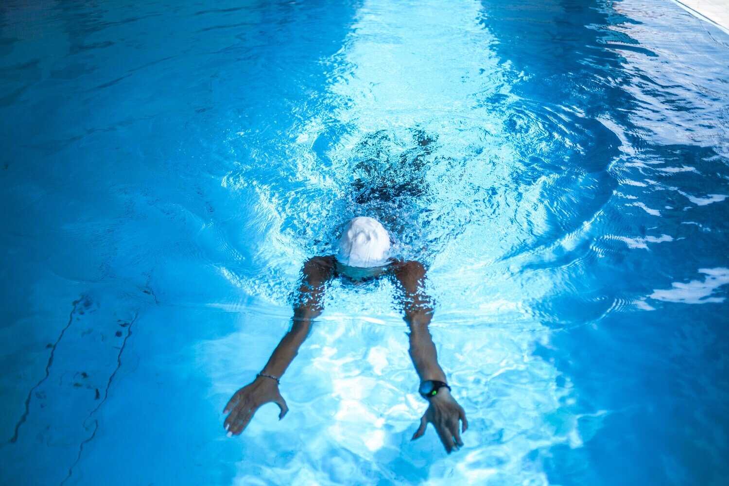 Eine Frau mit Schwimmkappe beim Schwimmen mit Smartwatch