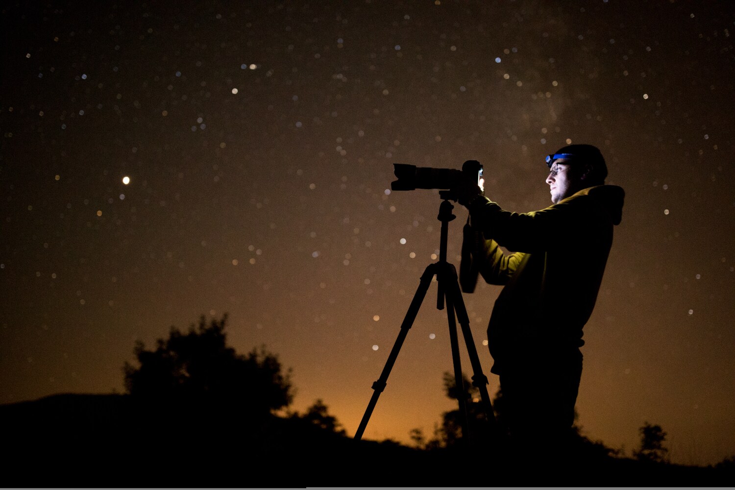 Ein Mann mit Stirnlampe fotografiert nachts Ein Mann mit Stirnlampe fotografiert nachts