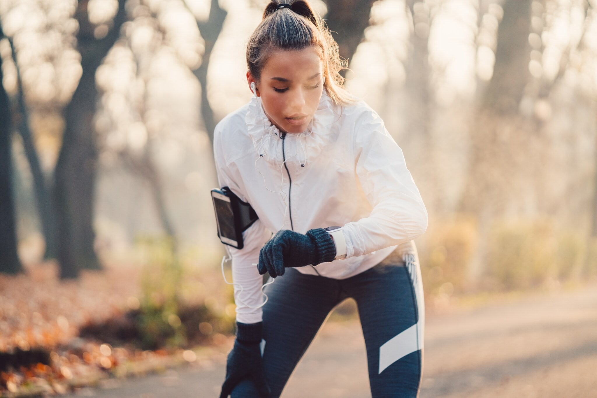 Eine Frau im Joggingdress blickt nach dem Laufen auf ihre Smartwatch Eine Frau im Joggingdress blickt nach dem Laufen auf ihre Smartwatch
