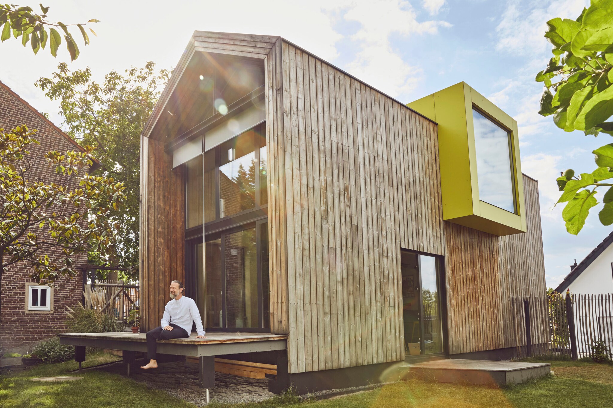 Ein Mann sitzt auf der Terrasse eines Tiny Houses Ein Mann sitzt auf der Terrasse eines Tiny Houses