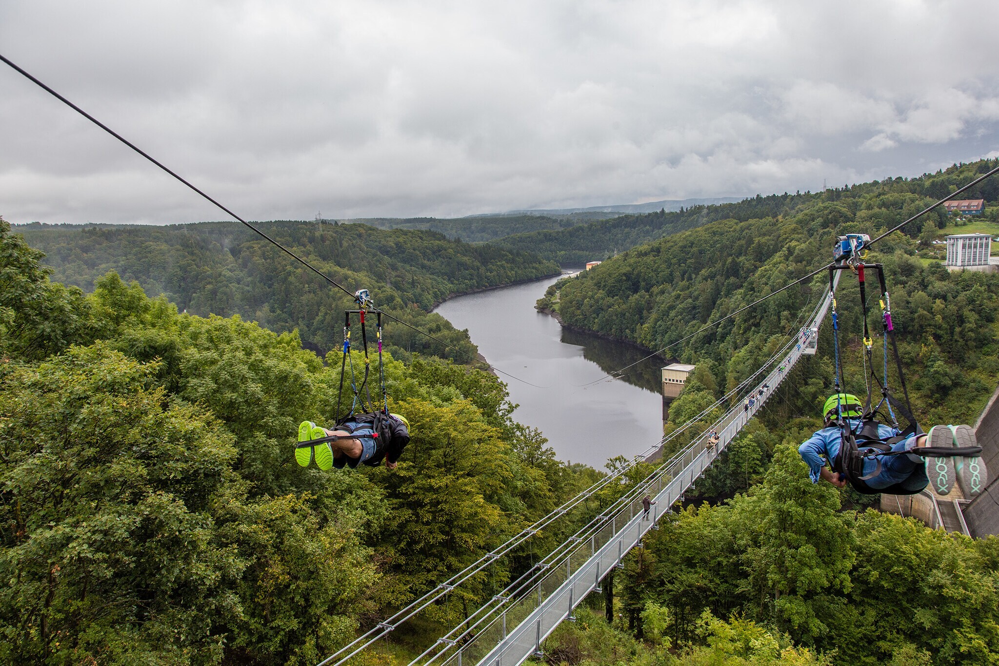 Zwei Zipliner überqueren an Stahlseilen die Rappbodetalsperre