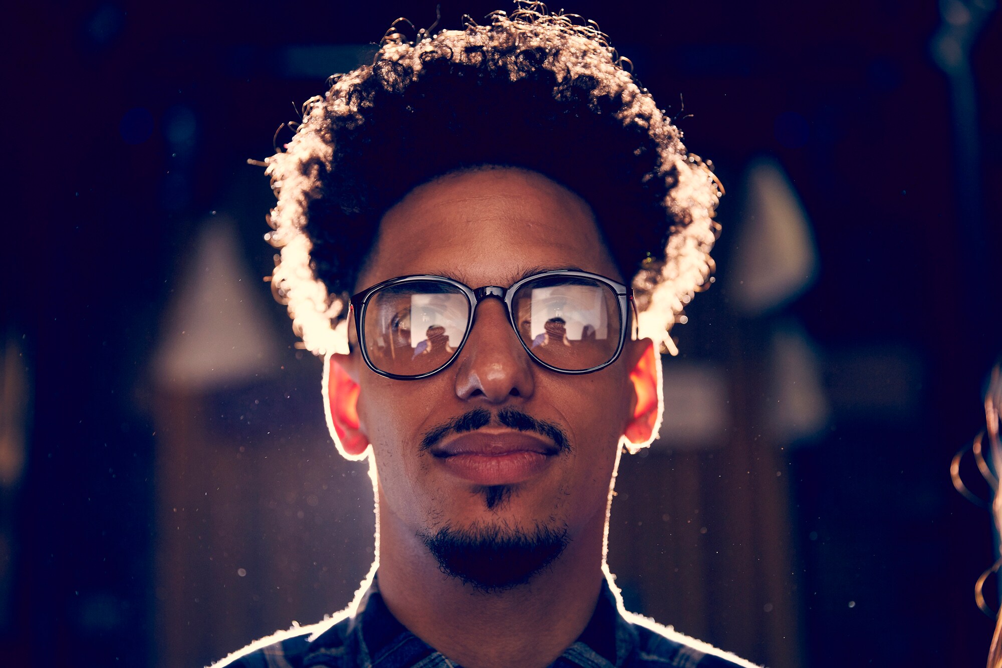 Ein junger Mann mit Bart und Brille schaut in die Kamera