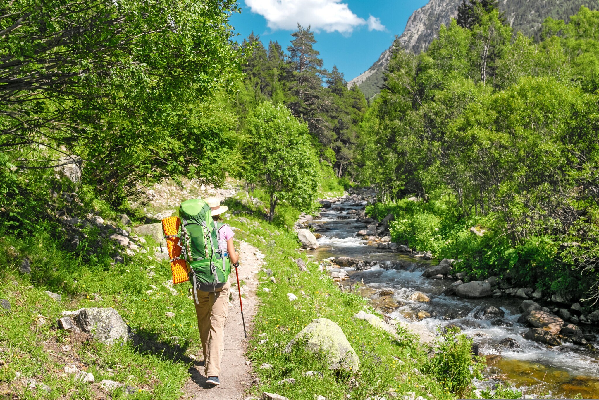 Eine Wanderin läuft neben einem kleinen Fluss in den Pyrenäen