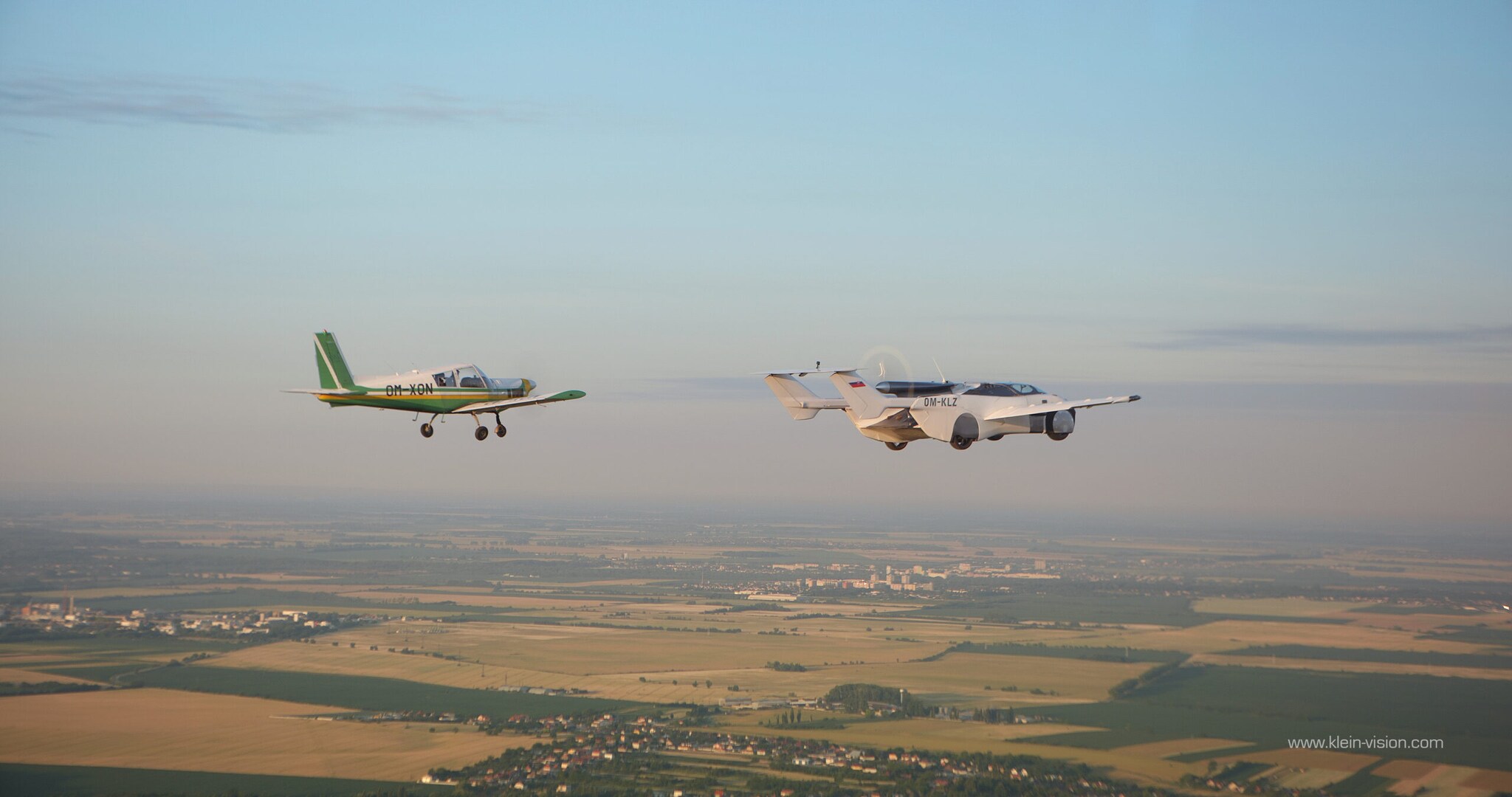 Ein AirCar Flugauto neben einem Sportflugzeug in der Luft