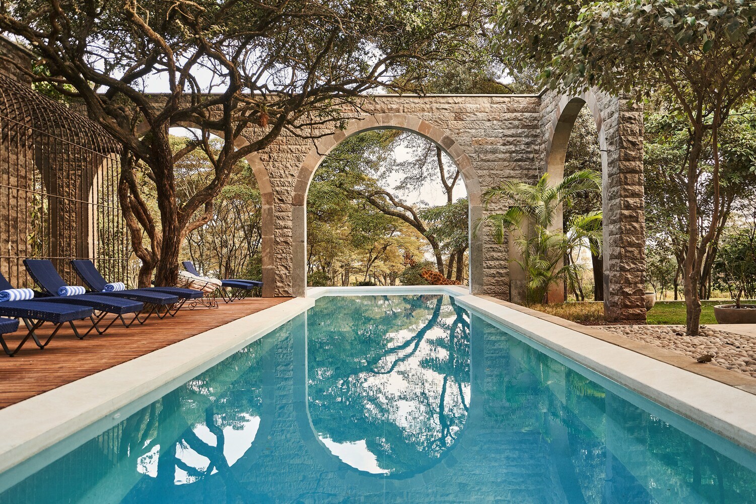 Ein langer Outdoor-Pool mit Rundbögen und einer Giraffe im Hintergrund