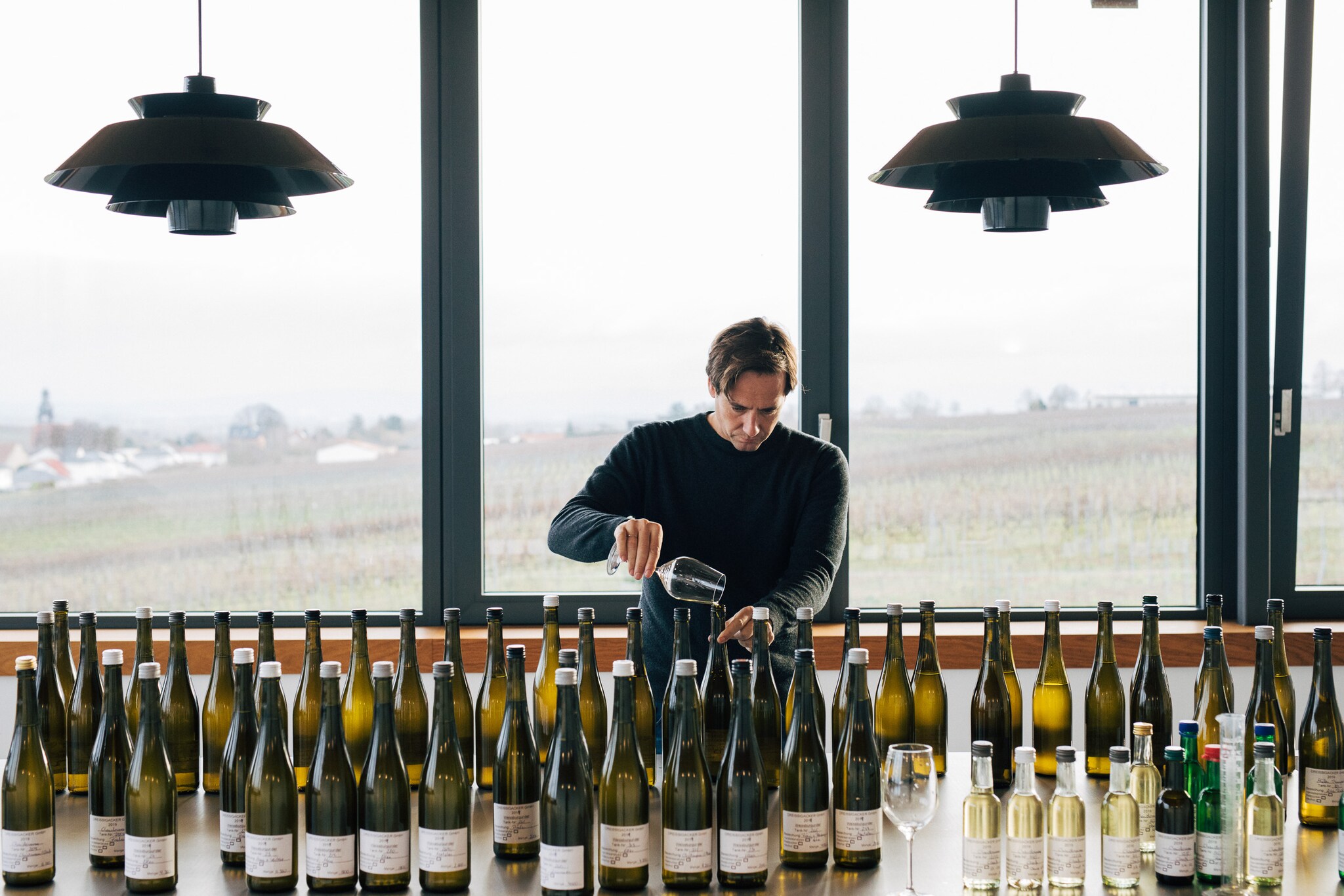 Winzer Jochen Dreissigacker beim Wein einschenken vor einem Tisch mit Weinflaschen