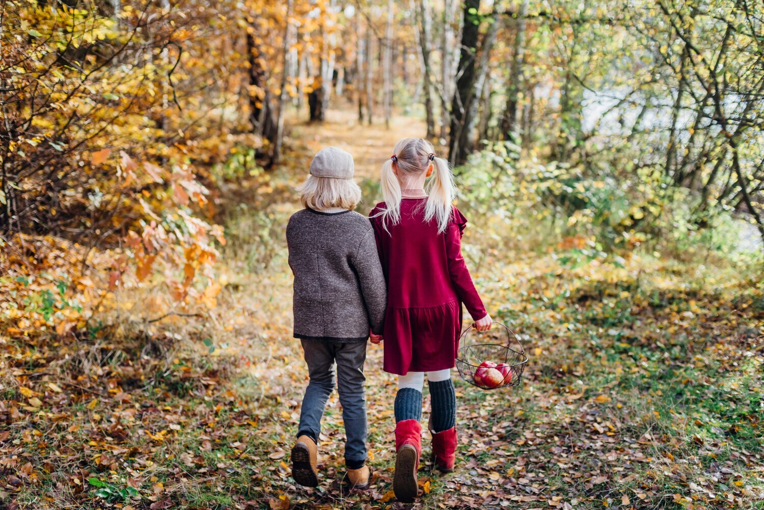 Rückansicht von zwei Kindern, die durch einen herbstlichen Wald gehen