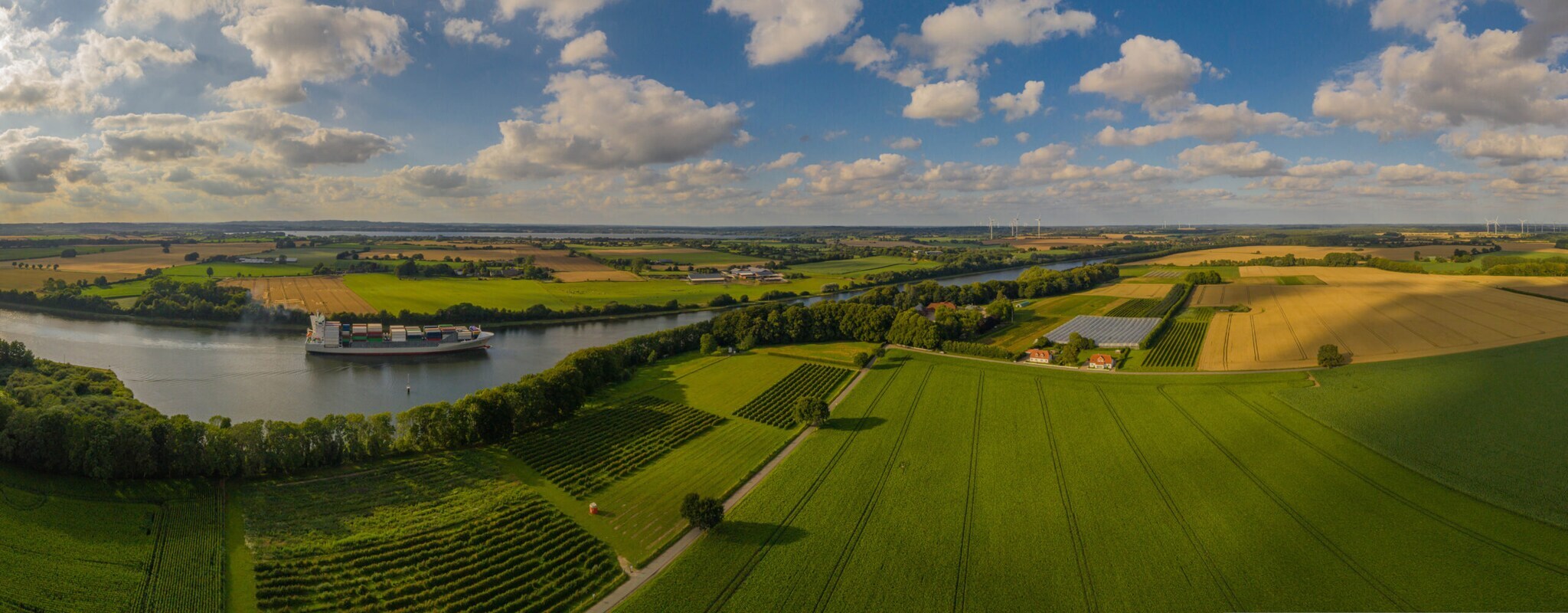 Ein Kanal zwischen Wiesen auf dem ein Frachtschiff fährt