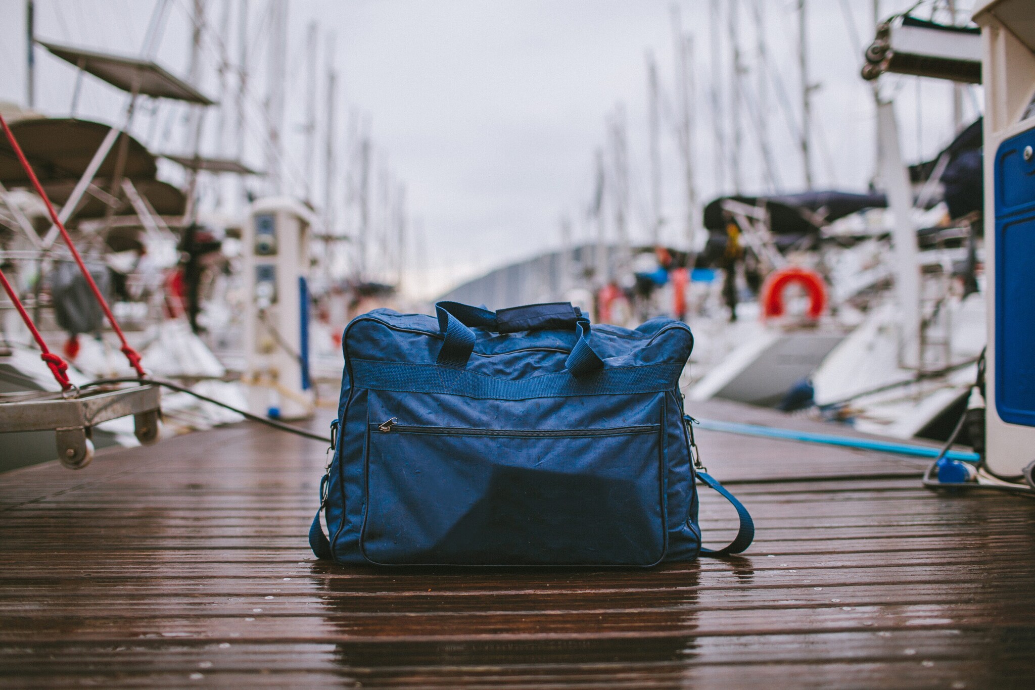 Eine gepackte Reisetasche steht auf einem Anlegeplatz für Segelboote