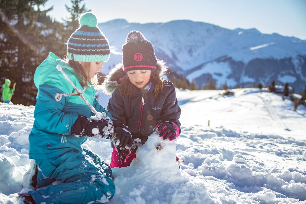 Zwei Mädchen in Schneeanzügen spielen im Schnee