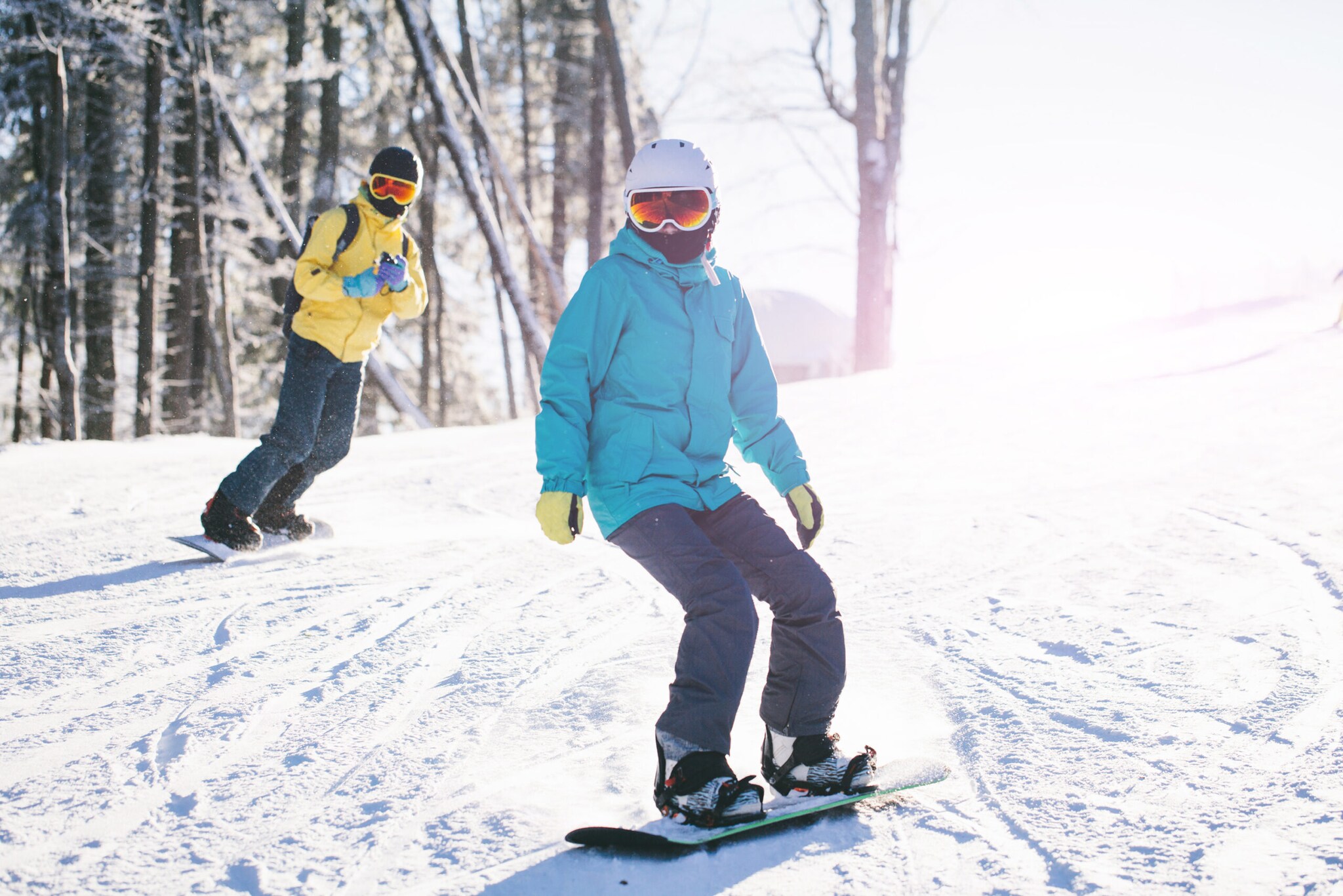 Zwei Menschen in Winterkleidung fahren auf Snowboards im Schnee