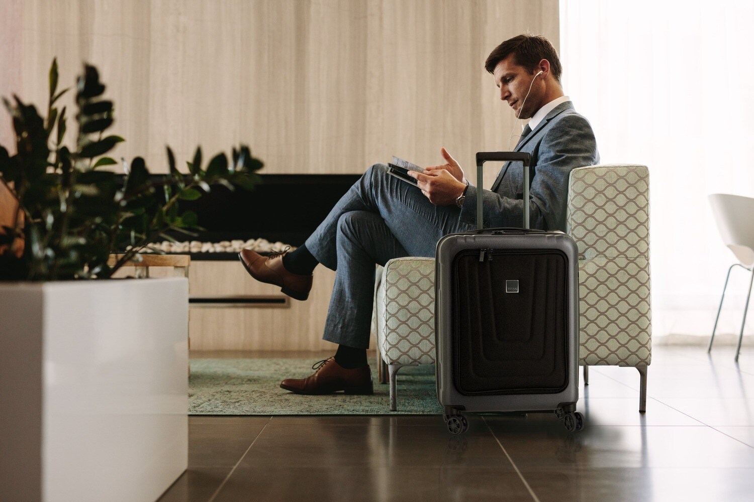 Ein Mann in einem Sessel, neben ihm steht ein Koffer Ein Mann in einem Sessel, neben ihm steht ein Koffer