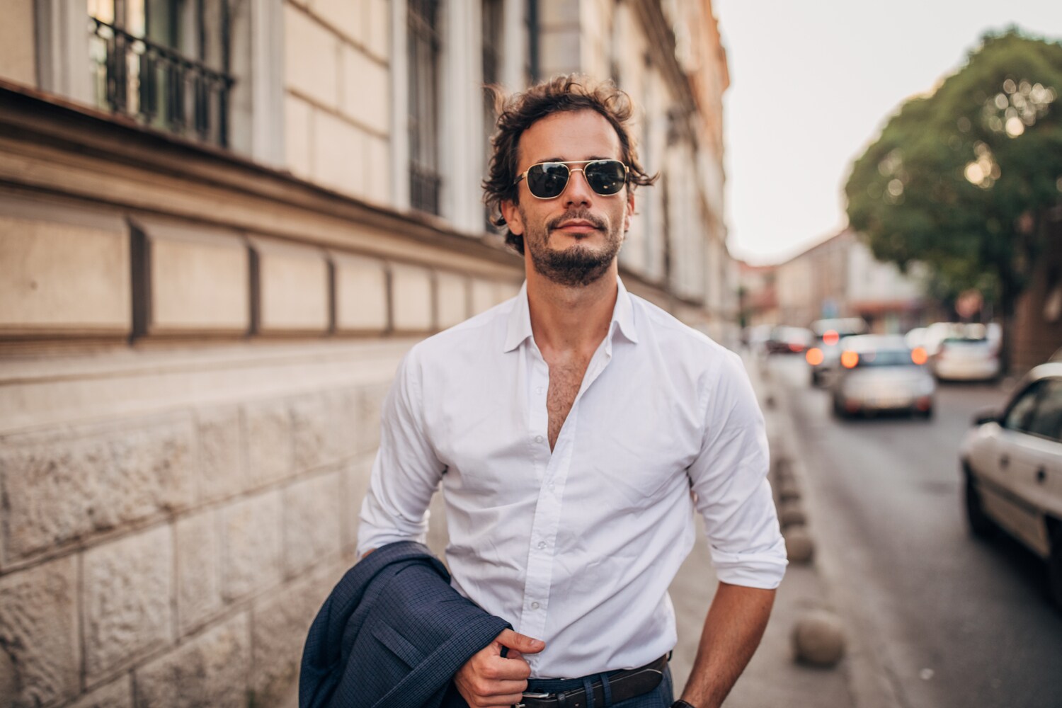Ein junger Mann mit Hemd und Sonnenbrille läuft die Straße entlang
