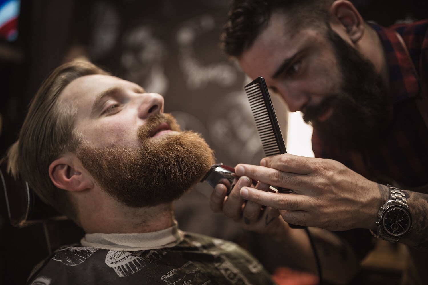 Ein Mann bekommt seinen Vollbart von einem Barbier getrimmt