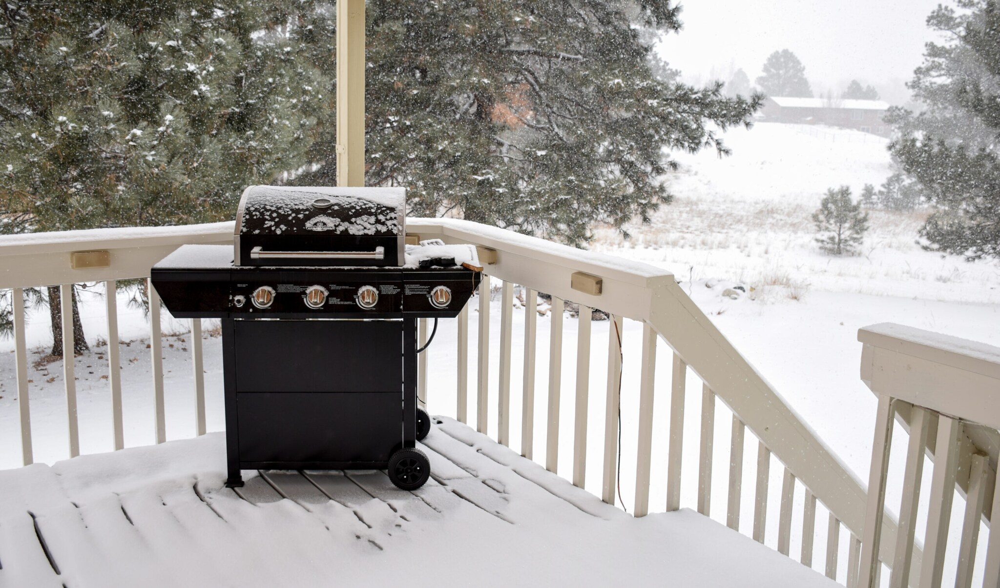 Ein verschneiter Grill steht auf einer Holzveranda