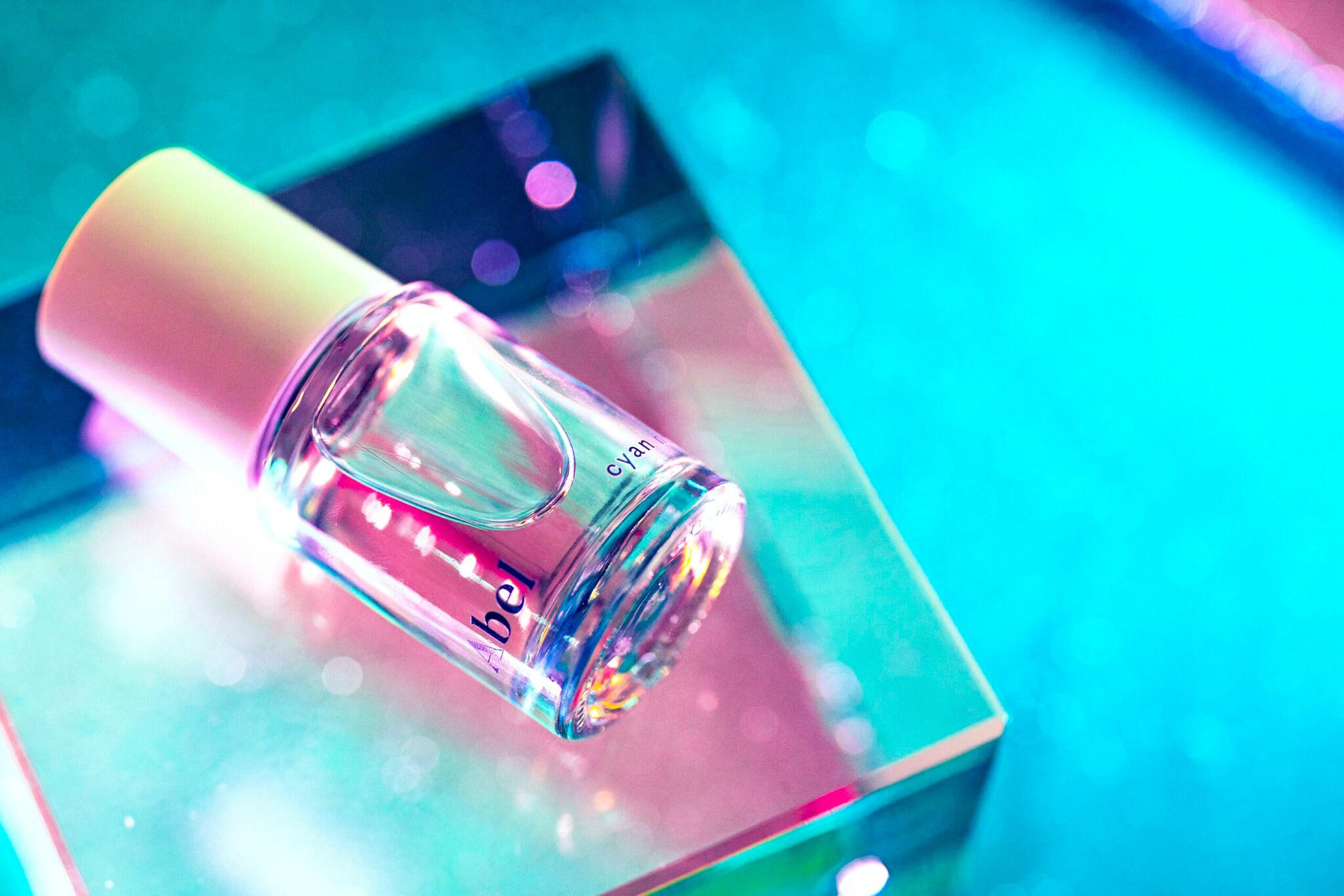 Eine transparente hohe Parfümflasche neben einer eckigen Umverpackung aus festem Karton