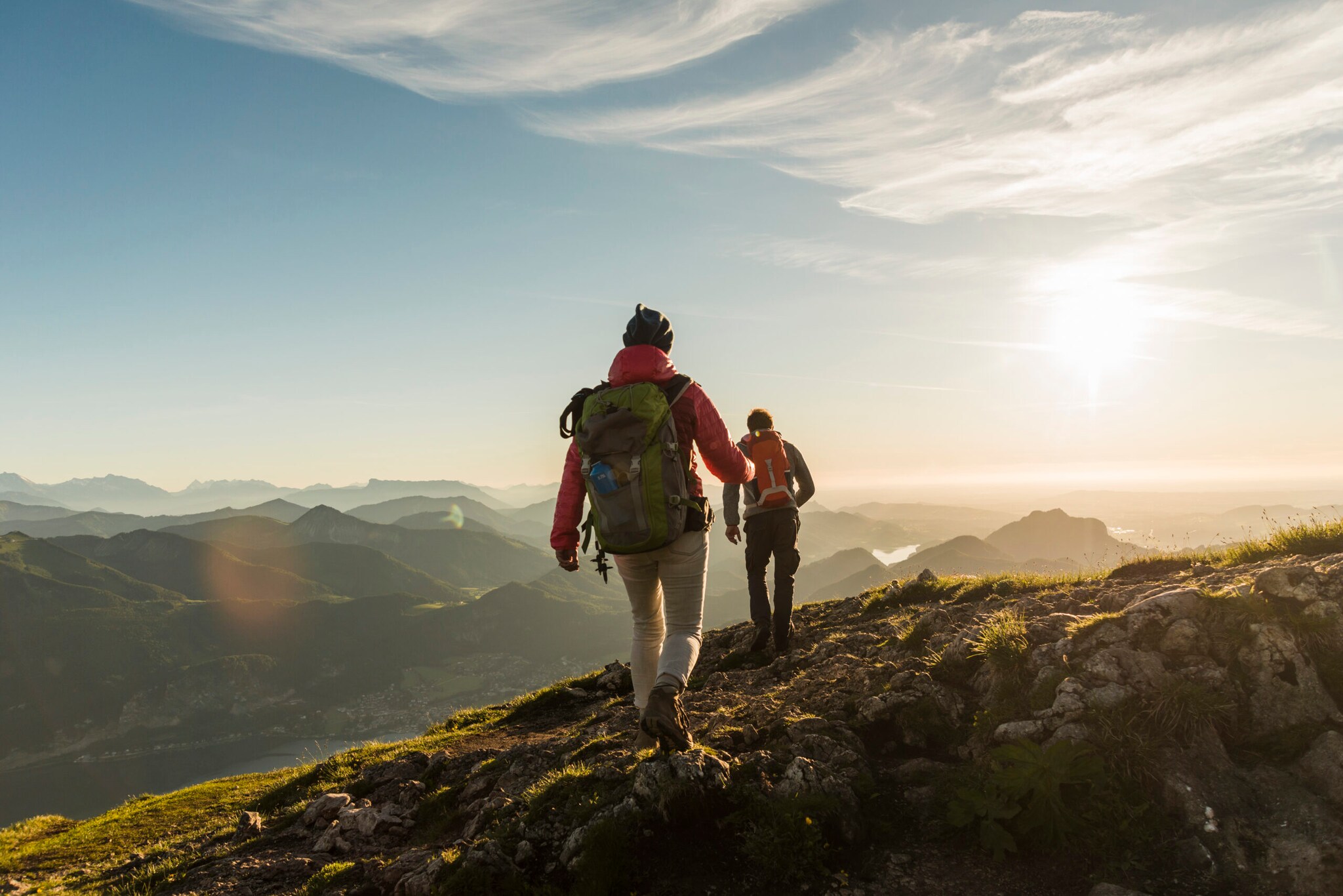 Zwei Personen wandern auf einem Berg mit beeindruckendem Panorama.