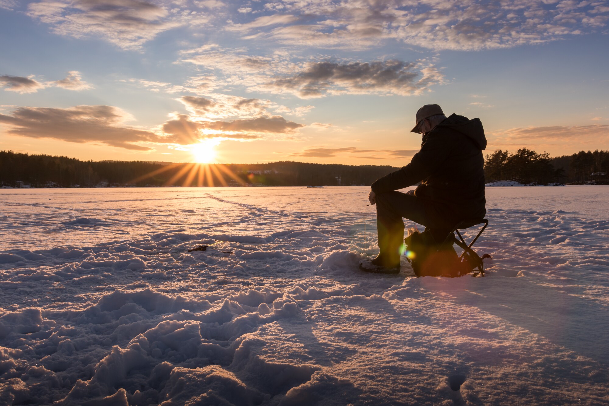 Ein Eisangler sitzt auf einem zugefrorenen See