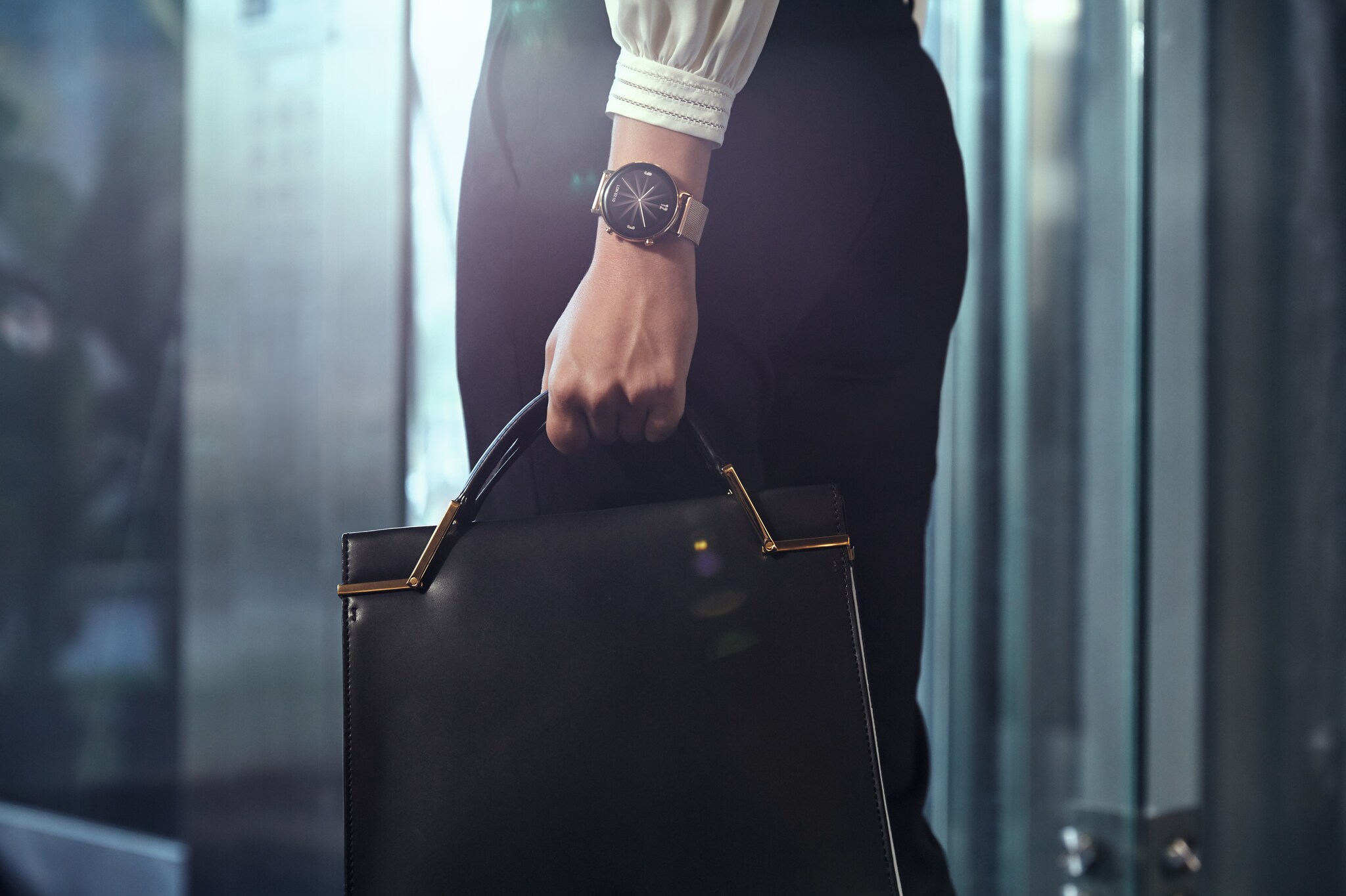 Eine Frau mit eleganter Armbanduhr trägt eine Ledertasche