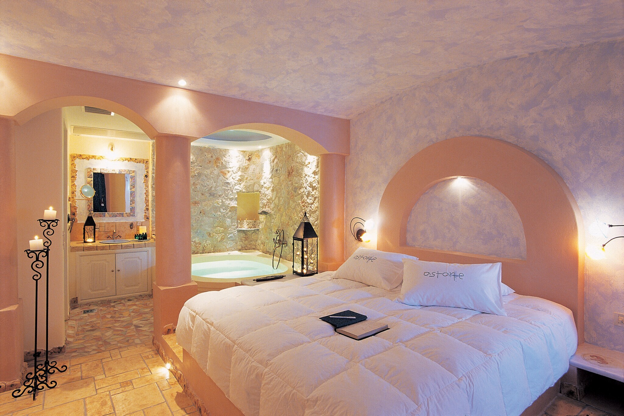 Hotelzimmer in Pastelltönen mit großem Bett und Whirlpool im Hintergrund