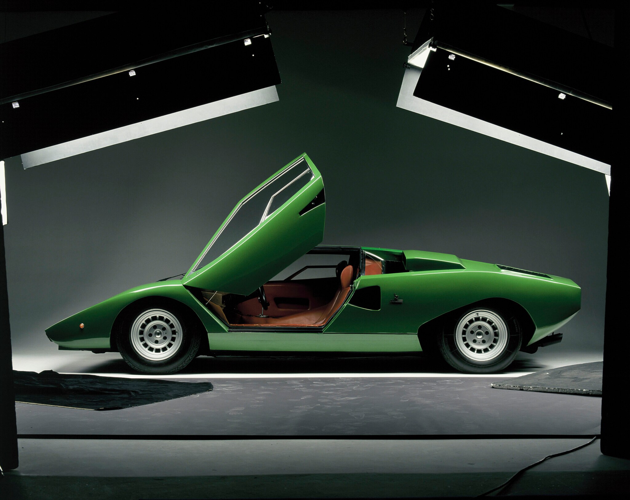 Seitenansicht eines grünen Lamborghini Countach LP400 mit geöffneten Türen in einem Fotostudio
