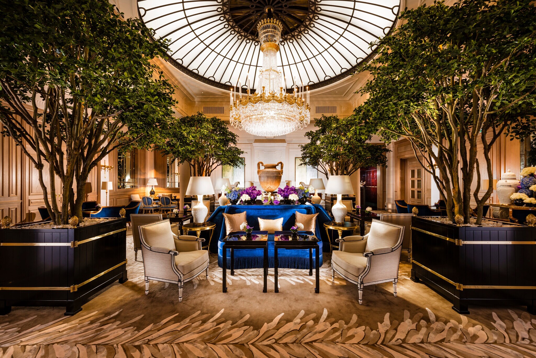 Innenaufnahme einer prunkvollen Hotelhalle mit Sesseln und Tischen Innenaufnahme einer prunkvollen Hotelhalle mit Sesseln und Tischen