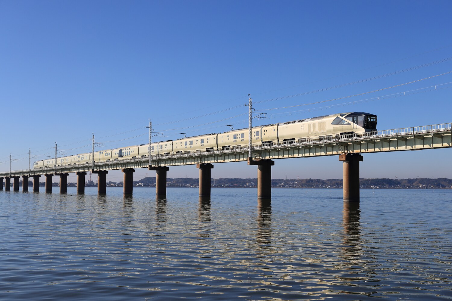 Ein moderner Zug fährt auf einer Eisenbahnbrücke über Wasser