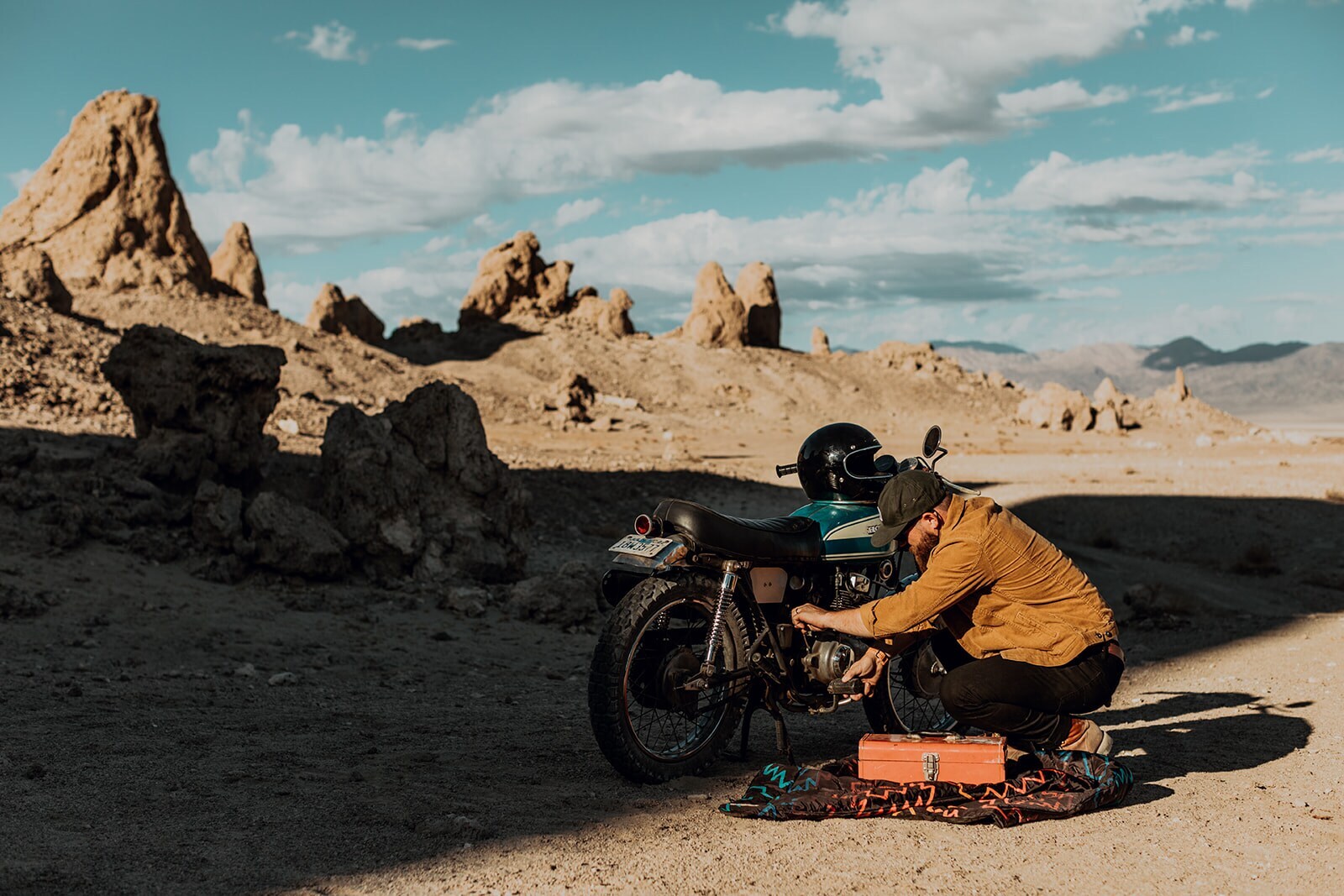 Ein Mann repariert Motorrad in Steinwüste
