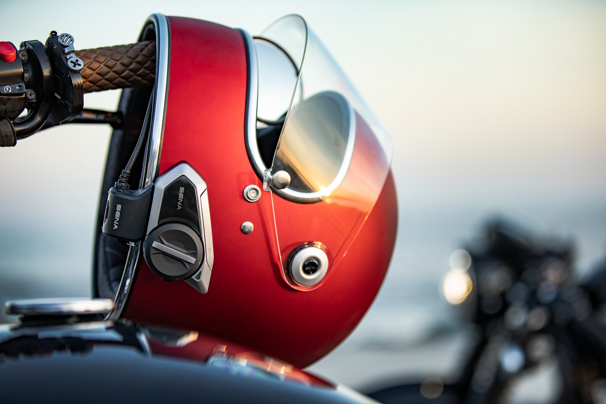 Nahaufnahme eines roten Helmes mit Sprechanlage am Motorradgriff