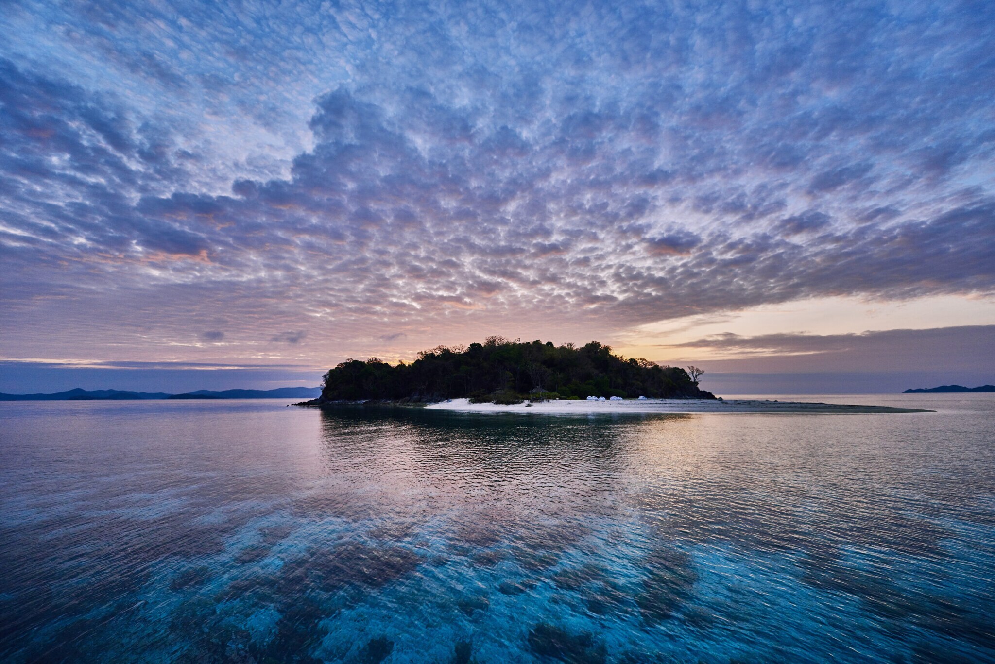 Eine tropische Insel mit Bäumen und Sandstrand in der Abenddämmerung