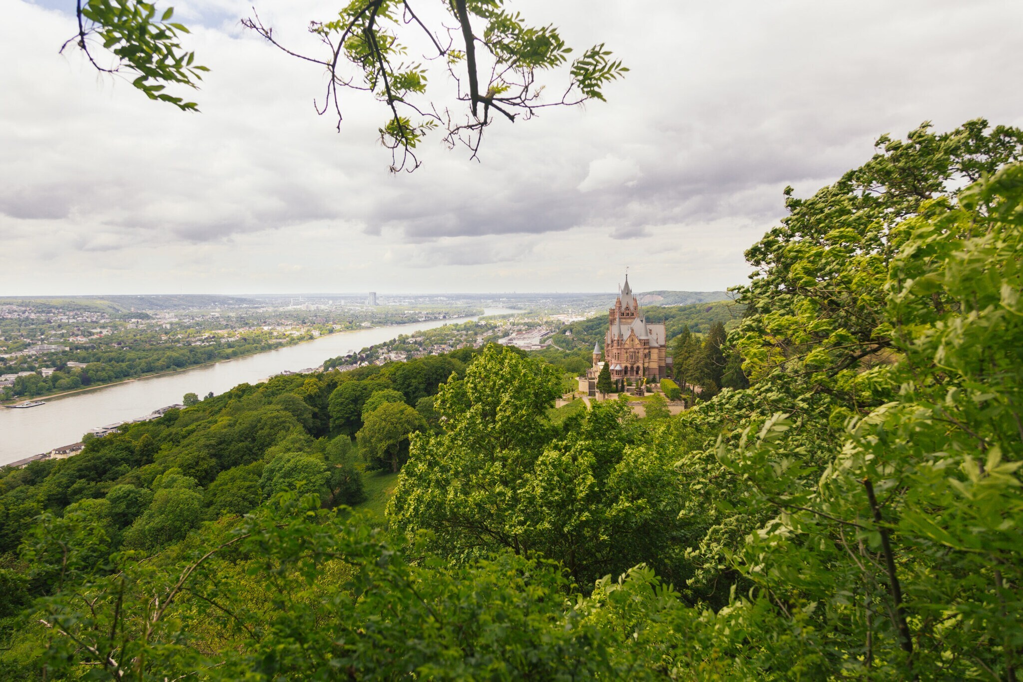 Panoramablick auf Schloss Drachenburg auf Plateau, umgeben von Wald, dahinter die Stadt Königswinter am Rhein Panoramablick auf Schloss Drachenburg auf Plateau, umgeben von Wald, dahinter die Stadt Königswinter am Rhein