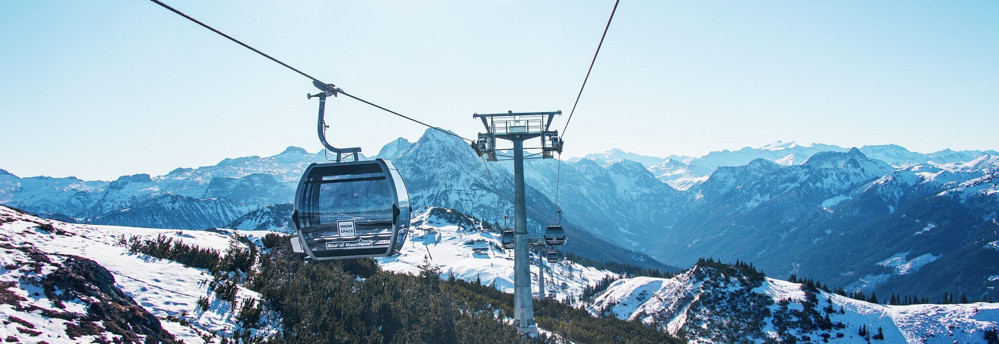 Skilift mit gläserner Gondel vor winterlichem Bergpanorama