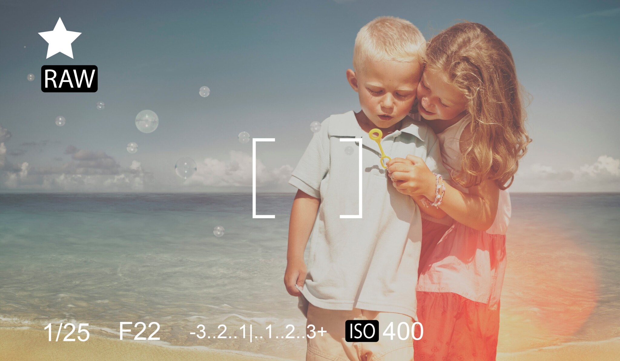 Der Blick durch eine Kamera, im Vordergrund sind die Einstellungswerte zu sehen, im Hintergrund zwei Kinder mit Seifenblasen am Strand