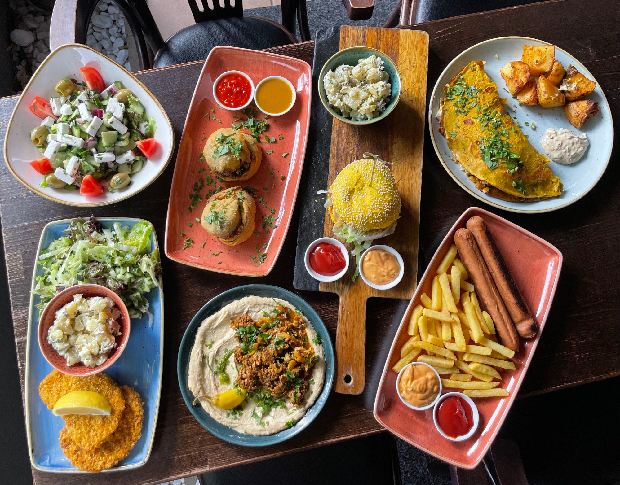 Auswahl an Gerichten, die auf unterschiedlichen Tellern auf einem Holztisch angerichtet sind Auswahl an Gerichten, die auf unterschiedlichen Tellern auf einem Holztisch angerichtet sind