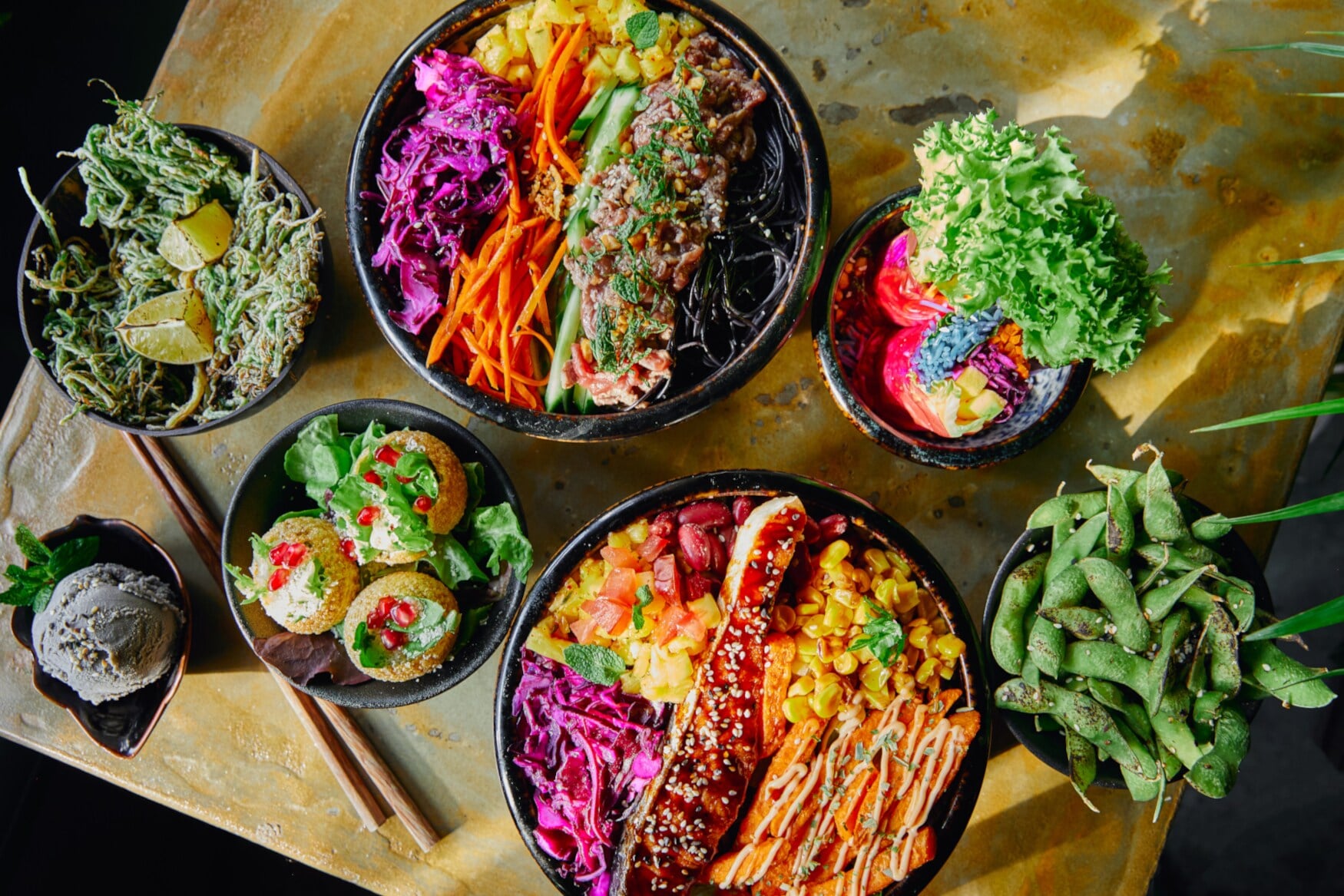 Verschiedene Speisen in leuchtenden Farben, die in Schalen auf einem Tisch angerichtet sind