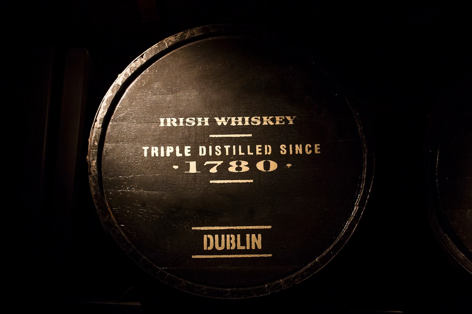 Ein Holzfass vor dunklem Hintergrund mit der Aufschrift Irish Whiskey Triple Distilled Since 1780 Dublin Ein Holzfass vor dunklem Hintergrund mit der Aufschrift Irish Whiskey Triple Distilled Since 1780 Dublin