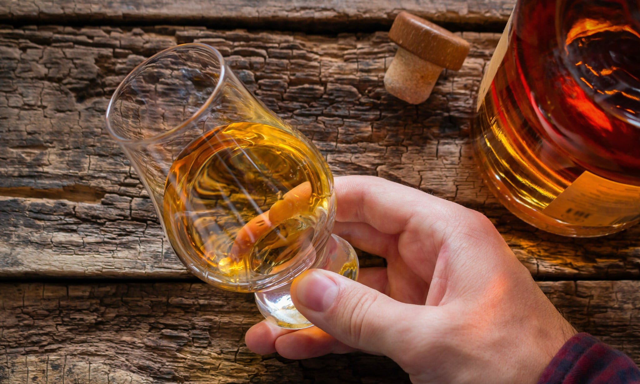 Eine Hand schwenkt Whisky in einem Nosing-Glas Eine Hand schwenkt Whisky in einem Nosing-Glas