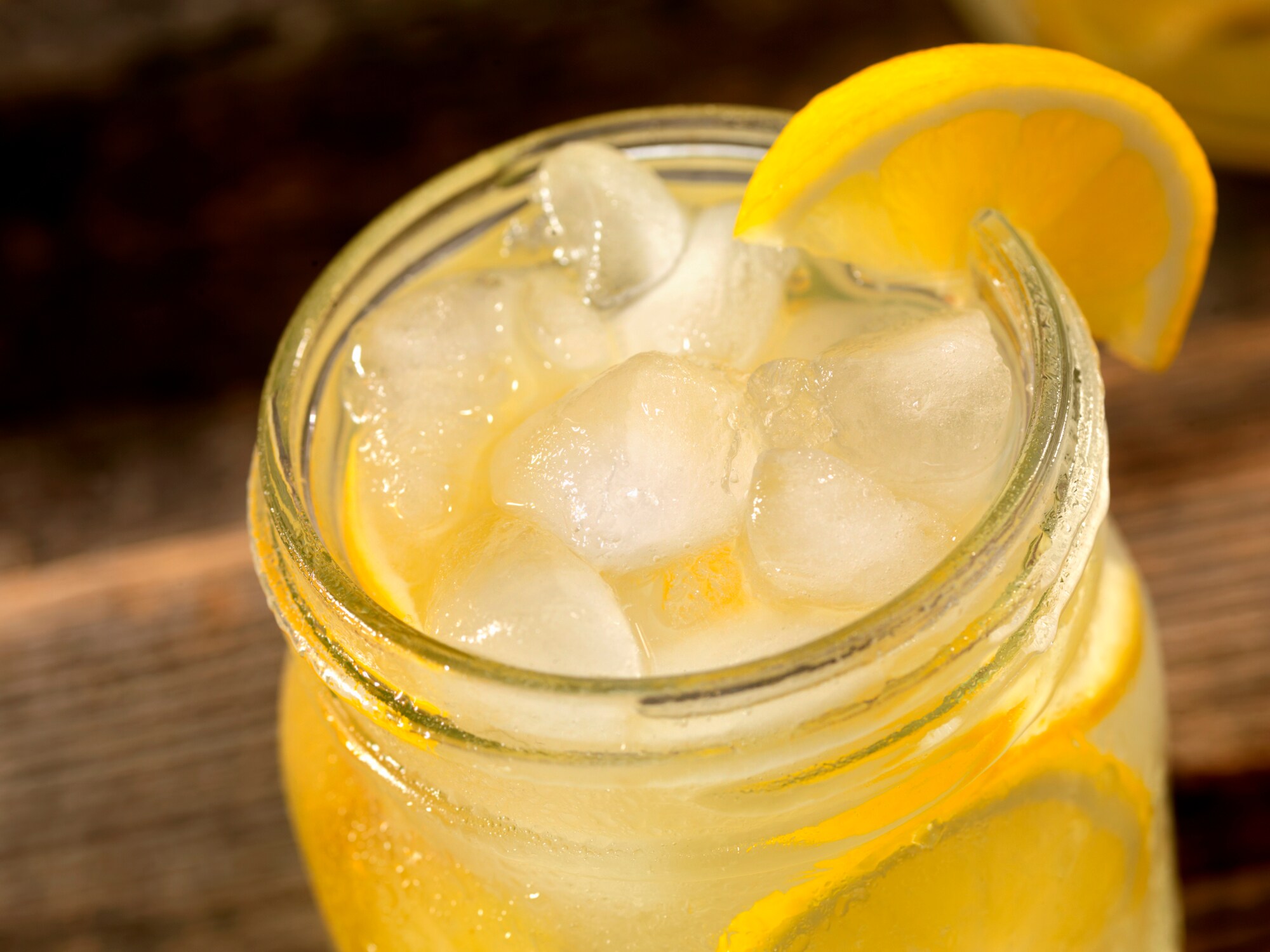 Detailaufnahme einer Limonade im Glas mit Eiswürfeln und Zitronenscheibe
