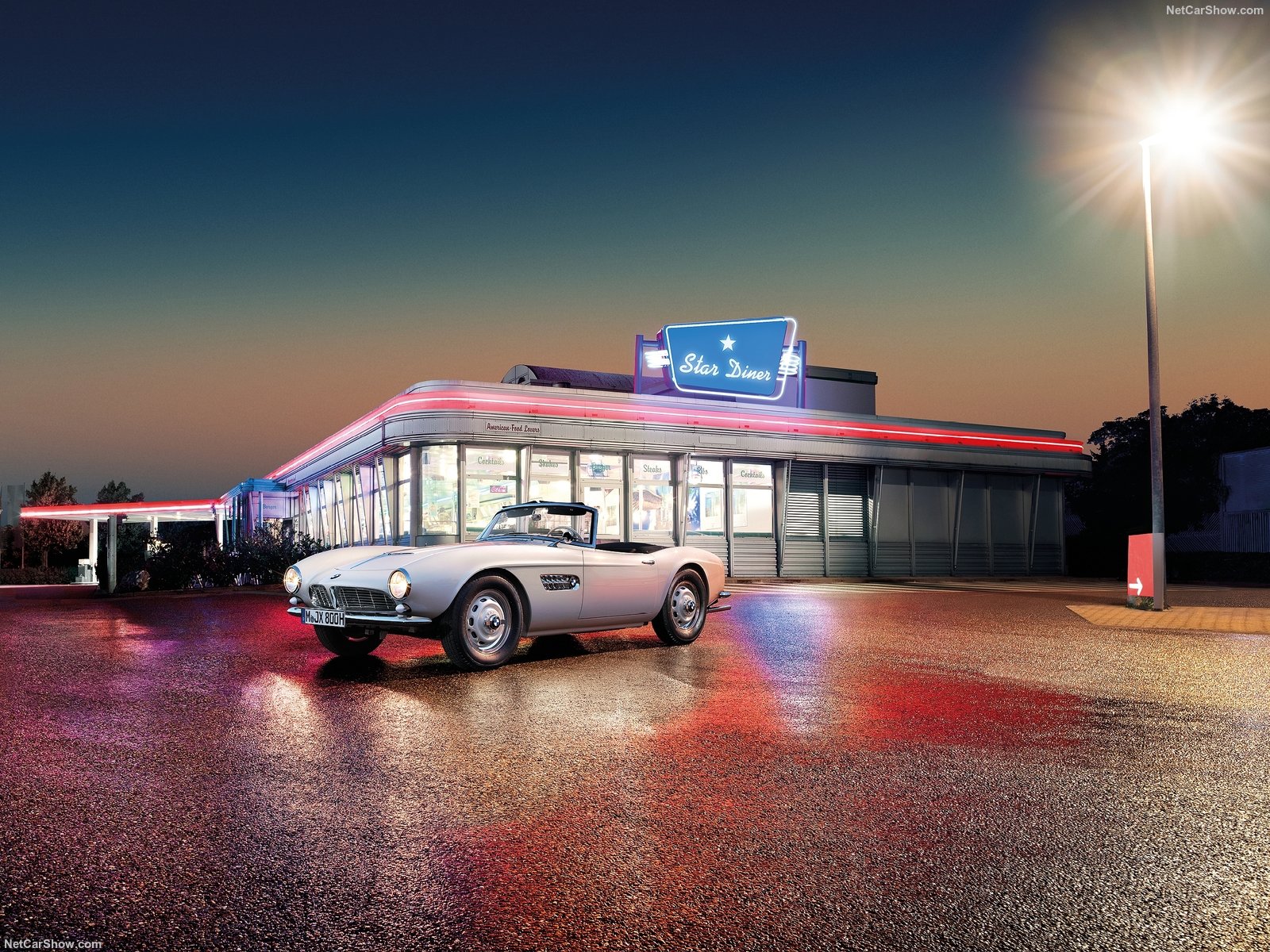 Der weiße BMW 507 steht vor einem amerikanischen Diner im Scheinwerferlicht Der weiße BMW 507 steht vor einem amerikanischen Diner im Scheinwerferlicht