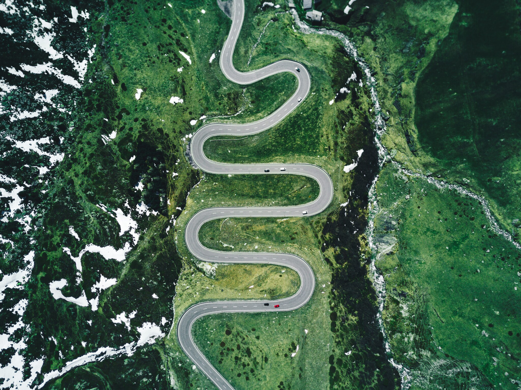 Eine Straße schlängelt sich durch grünen Wiesen und an Bergkuppen vorbei. Eine Straße schlängelt sich durch grünen Wiesen und an Bergkuppen vorbei.