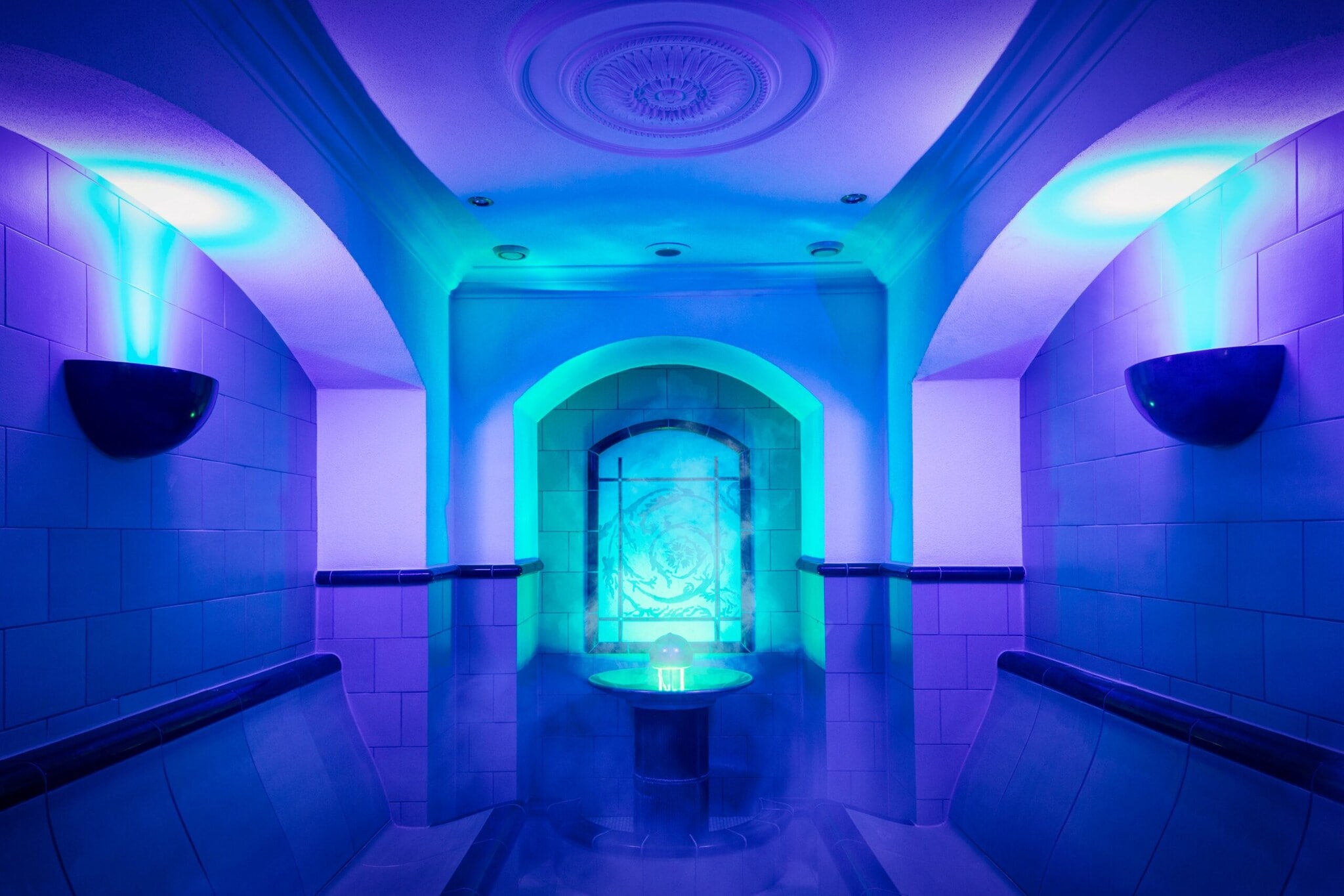Innenaufnahme einer gekachelten Dampfsauna mit Jugendstildekor und blauer Beleuchtung Innenaufnahme einer gekachelten Dampfsauna mit Jugendstildekor und blauer Beleuchtung