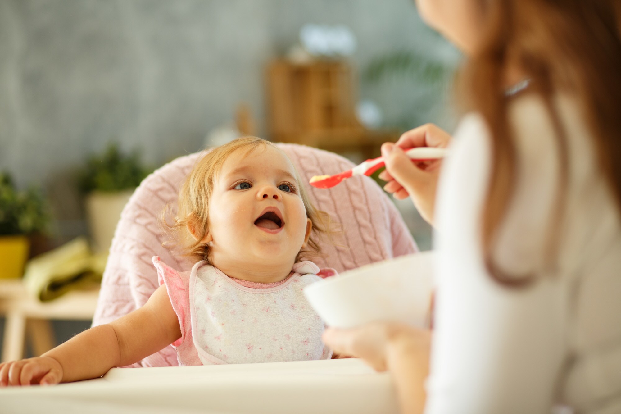Mutter füttert ihr Baby am Tisch mit Brei