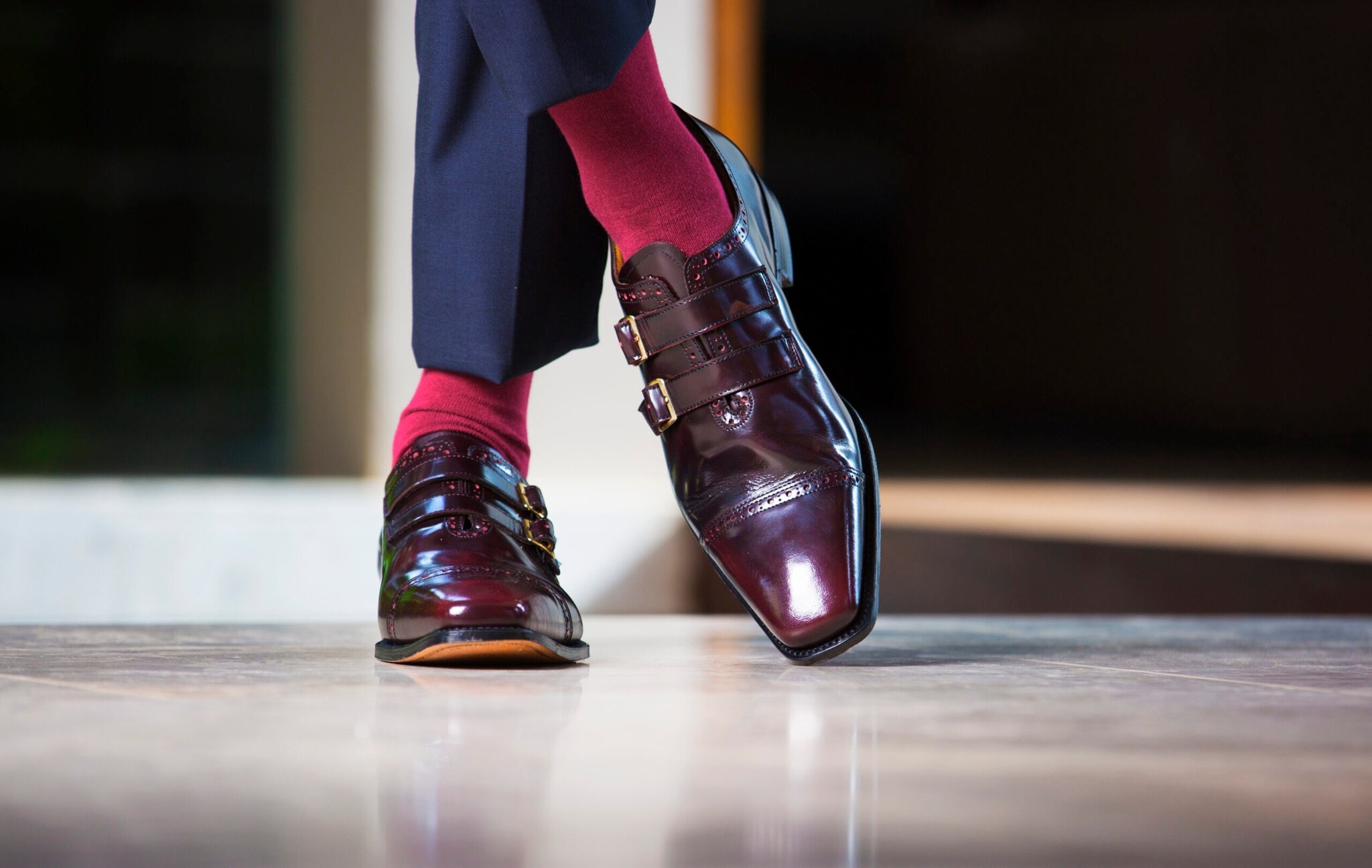 Dunkle Herrenschuhe, zu denen rote Socken und eine blaue Anzughose getragen werden. Dunkle Herrenschuhe, zu denen rote Socken und eine blaue Anzughose getragen werden.