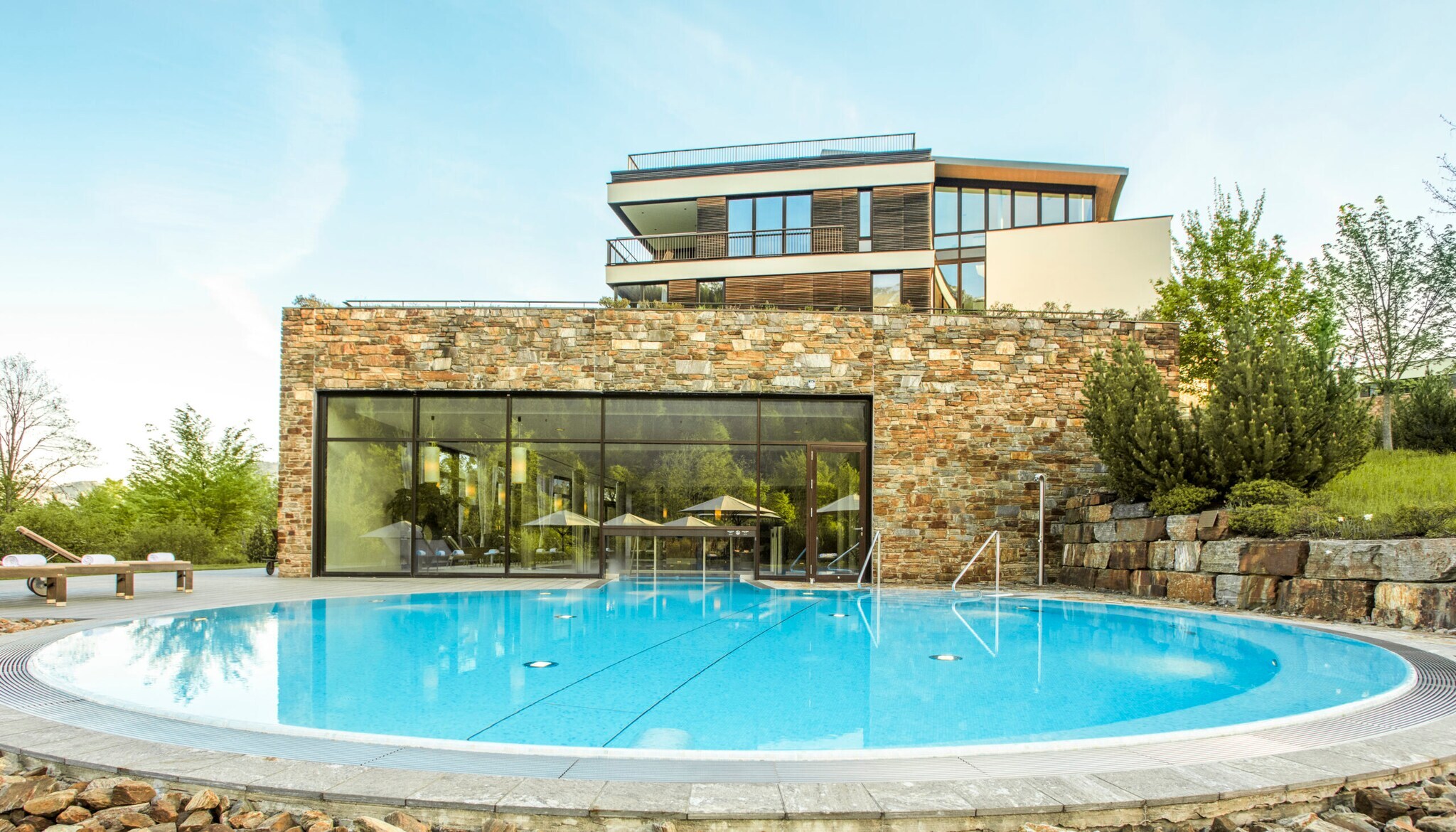 Ein Outdoorpool vor einem Gebäude mit Glasfront Ein Outdoorpool vor einem Gebäude mit Glasfront