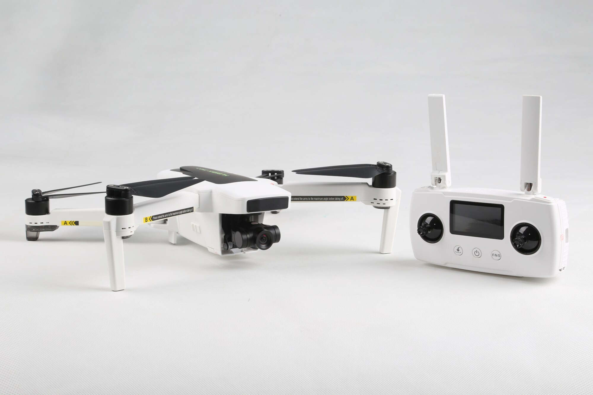 Weiße Kameradrohne mit zugehöriger Fernbedienung vor weißem Hintergrund
