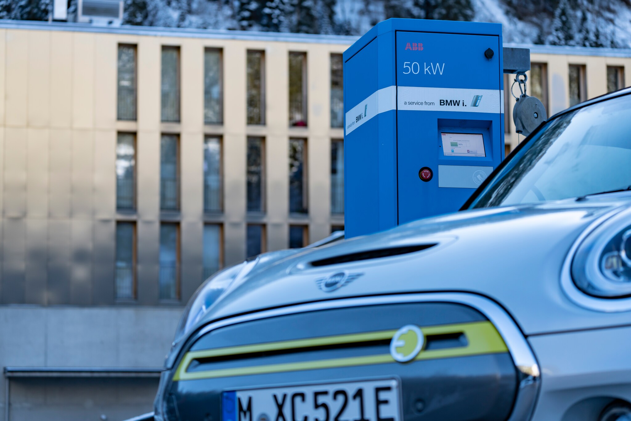 Ein Mini E-Auto steht im Winter an einer Ladesäule.